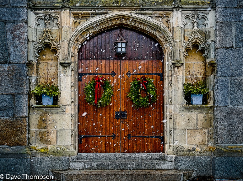 A photograph of snow falling in front of the classic wooden doors and stonework of the Phillips Exeter Academy Chapel in Exeter, NH.